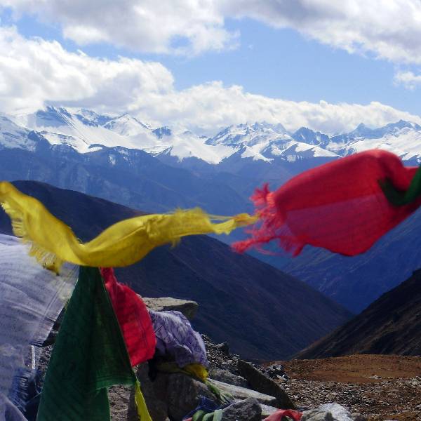 Gebetsfahnen entlang des Druk Path Treks mit Blick auf die schneebedeckten Gipfel des Himalayas in Bhutan