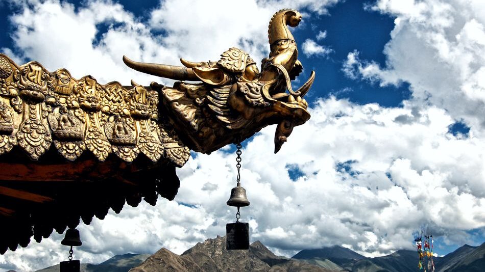 Vergoldeter Drachenkopf an einem tibetischen Kloster Vergoldeter Drachenkopf auf dem Dach eines tibetischen Klosters vor der Berglandschaft des Himalayas.