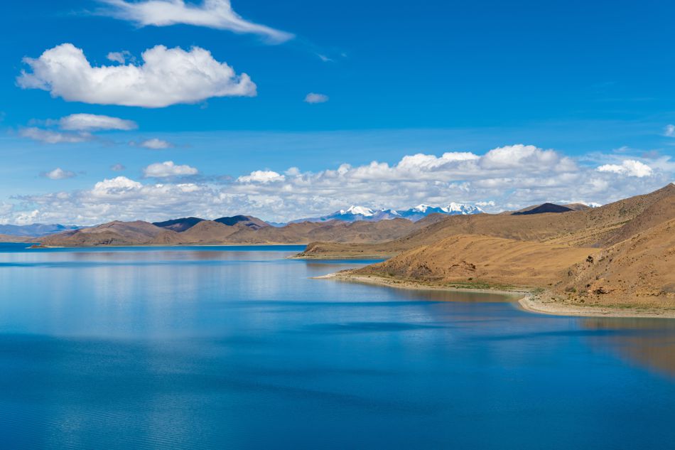 Der türkisblaue Yamdrok-See in Tibet vor der beeindruckenden Kulisse des Himalayas.