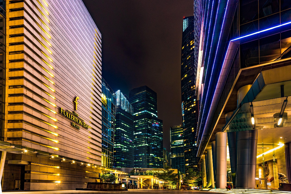 The Fullerton Bay Hotel und beleuchtete Wolkenkratzer in Singapur bei Nacht